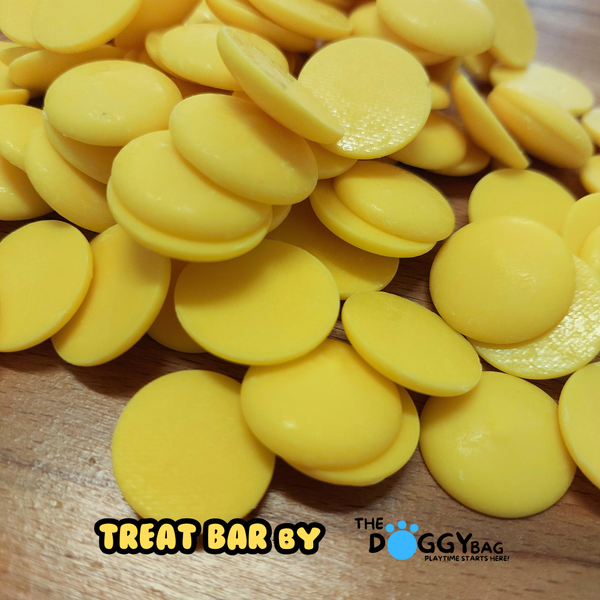Yellow Yoghurt banana dog treats on a wooden surface with 'Treat Bar by The Doggy Bag' branding.