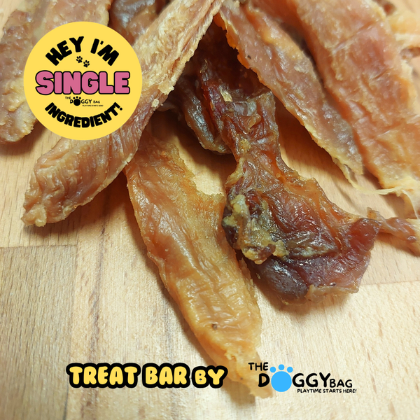 Dried duck fillet jerky dog treats on a wooden surface with 'The Doggy Bag' branding.