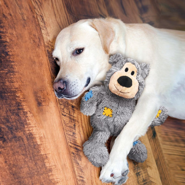 KONG Wild Knots Bear Squeaky tough rope plush dog toy. Durable Dog Toy. Labrador lying down with his Grey Wild Knot Bear.